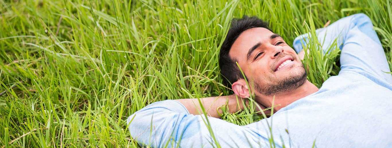 Young man in light blue shirt laying down on the grass